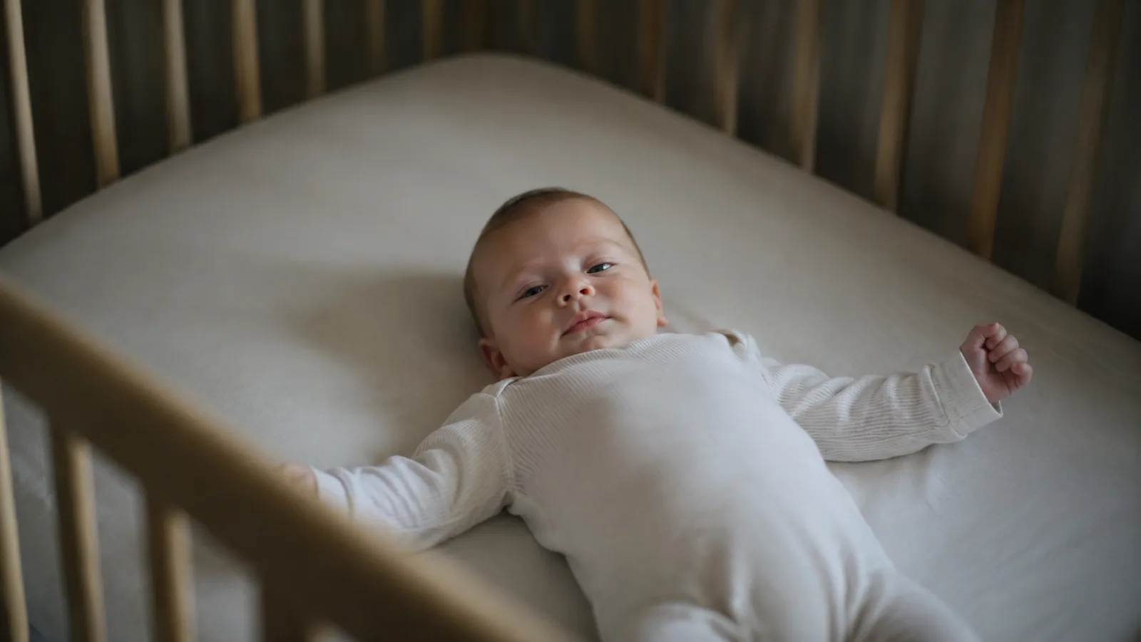 Bebê de barriga para cima no berço, ainda acordado